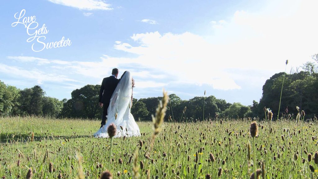 bride and groom take a stroll through the fields near the lake with her long cathedral length veil blowing in the wind