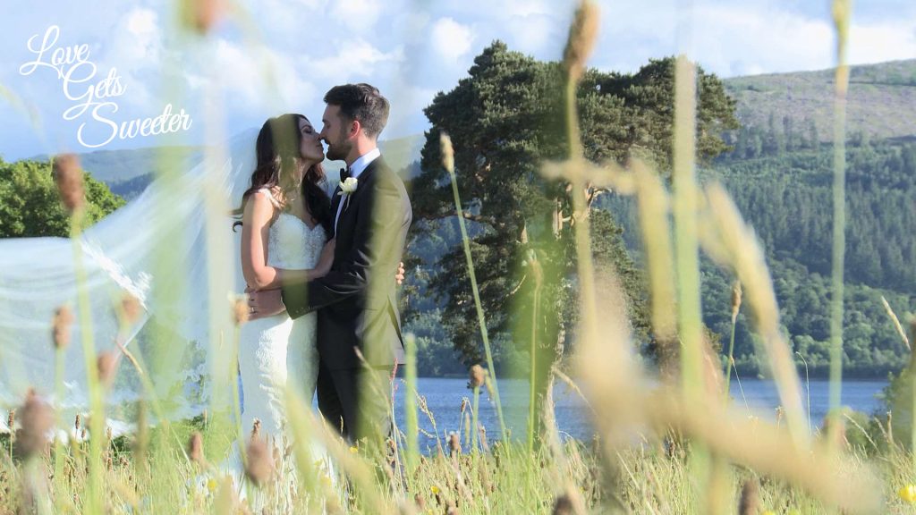 bride and groom having a kiss in the field by Armathwaite Hall in front of Bassenthwaite Lake for their wedding videographer